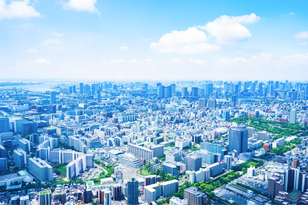 青空の下に広がる都市の街並みを一望する空撮