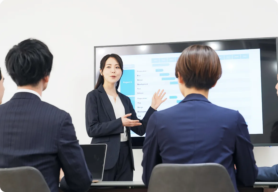 会議室でモニターを使いAI研修を行う講師と受講者
